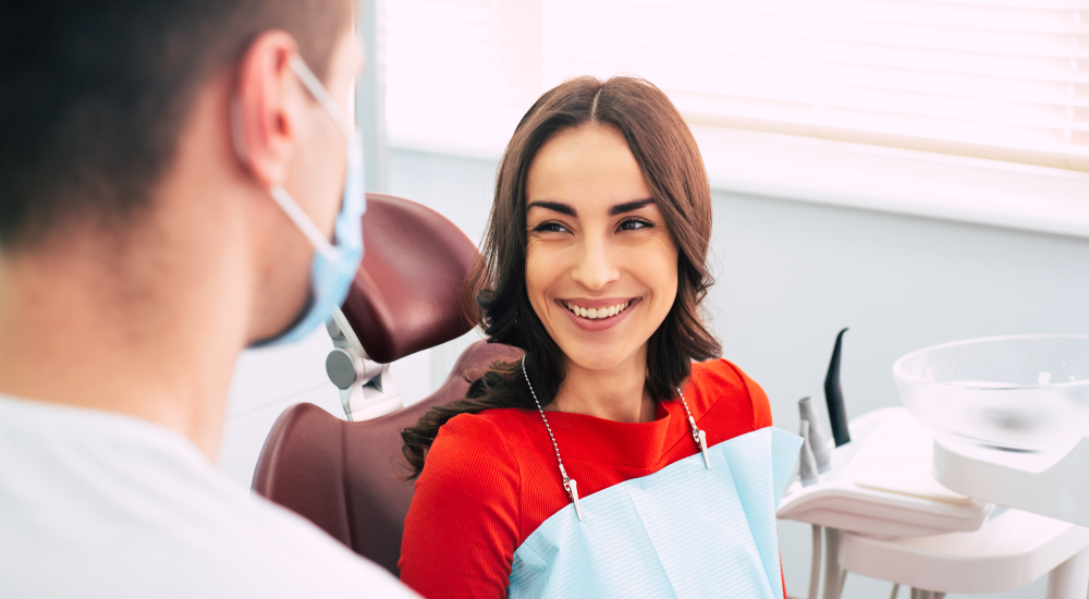 patient in red top wearing dental bib smiles